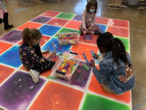 Students in Kristy Del Olmo's 2nd grade class assemble Qubits construction pieces while sitting on a liquid tile interactive mat, both items paid for by STEM's PTO