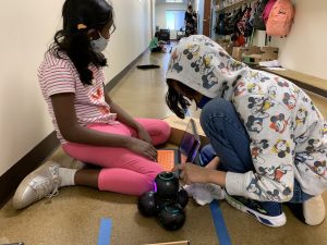 Students in the hallway outside of Mrs. Gasser's classroom work in teams to program Cue Robots