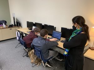STEM eighth grader Alex Price helps another student fix a coding issue for a video game